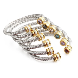 Macro detail of silver cable bracelets featuring gold accents and colorful gemstones