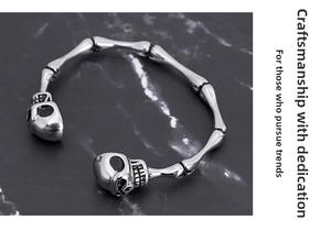Macro detail of gothic skull bone open bracelet in silver finish on dark marble base