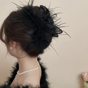 Detail of elegant black feather hair claw clip with mesh on French retro hairstyle
