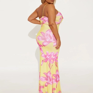 Detail of yellow summer dress with pink lily print showing thin straps and sleek fit