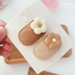 Close-up of two flower hair clips with felt bases on a white card display