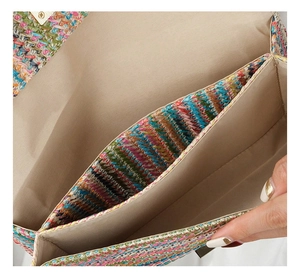 Internal view of colorful woven straw clutch showing dual compartments and fabric lining