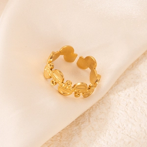Vue détaillée d'une bague géométrique ajourée en acier plaqué or sur fond de soie