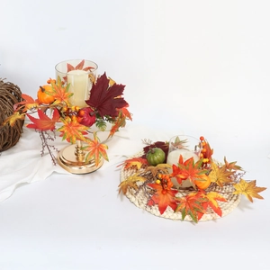 Close-up of autumn candle ring featuring artificial maple leaves, pumpkins and berries