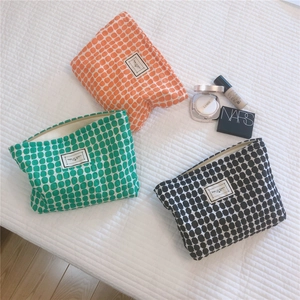 Flat lay of geometric polka dot cotton pouches in orange green and black with label