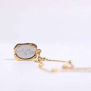 Close-up of golden vintage mirror pendant with engraved rose and floral details