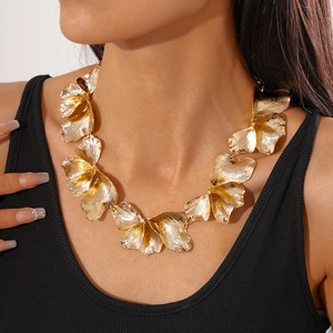 Detail of golden metal floral statement necklace with textured petal design on model