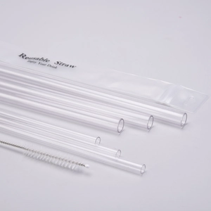 Reusable transparent straws set with cleaning brush and packaging on a grey surface