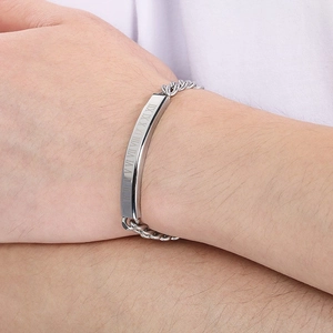 Close-up of men's stainless steel bracelet with engraved Roman numerals on a curved plate