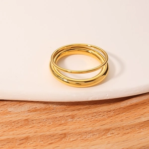 Three-piece set of minimalist gold stainless steel rings on a white stone display