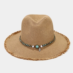 Detail of straw sun hat with bohemian beadwork, turquoise accents, and fringe brim