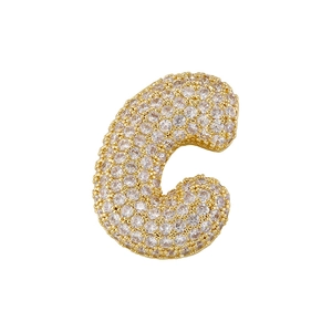Macro detail of gold letter C pendant with shimmering pavé cubic zirconia inlay