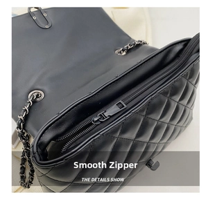 Detail shot of smooth black resin zipper and quilted leather pattern on chain handbag
