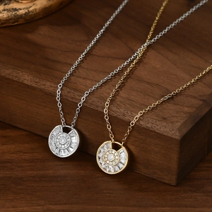 Close-up of gold and silver plated necklaces with zircon pendants on wood surface