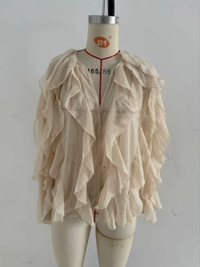 Close-up of elegant layered ruffles on apron and sleeves of beige chiffon shirt