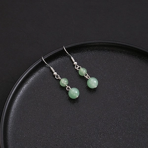 Detail shot of green beaded tassel earrings on black plate for Chinese traditional style