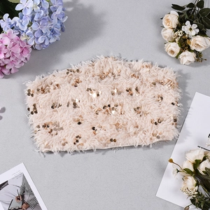 Dettaglio del top a fascia color champagne con pelliccia sintetica e paillettes dorate