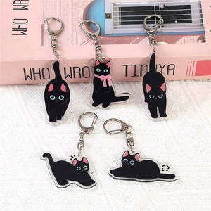 Set of five cute black cat acrylic keychains with pink bowties on a soft pink background