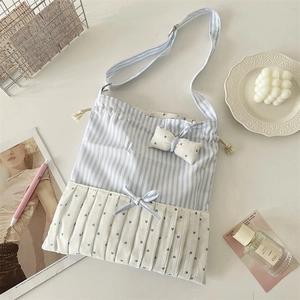 Detail of blue striped tote bag with bow accents and ruffled trim on a stylish setup