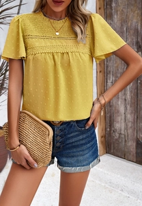 Detail of yellow short-sleeved top featuring textured fabric and delicate lace trim