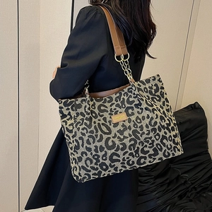 Leopard print tote bag with brown leather and chain straps shown on a female model