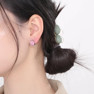 Close-up of polished silver hoop earring with pavé-set pink cubic zirconia on ear