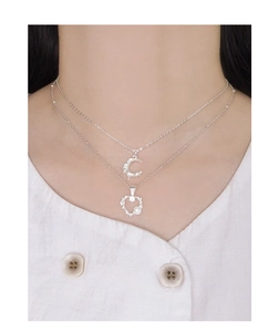 Detail of silver S925 double layer necklace with moon and hollow heart pendants on model
