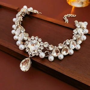 Detailed view of silver flower necklace with teardrop crystal on dark wood tray