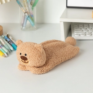 Close-up of a cute brown plush bear pencil case with zipper on a white desk