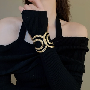 Close-up of a wide gold twisted rope texture open cuff bracelet on a female wrist