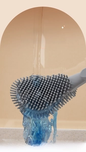 Flat silicone toilet brush head being rinsed under water to show easy cleaning feature