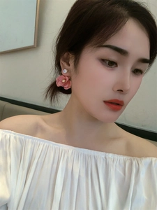 Detailed close-up of pink camellia petal earrings with sparkling zircon on a model