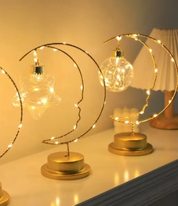 Detail of creative moon-shaped LED lamps with hemp rope and warm light strings on a gold base