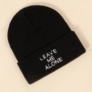 Detailed close-up of white 'LEAVE ME ALONE' embroidery on black knitted beanie cap