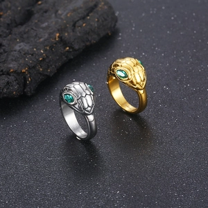 Detailed view of punk snake rings with green gem eyes in gold and silver steel