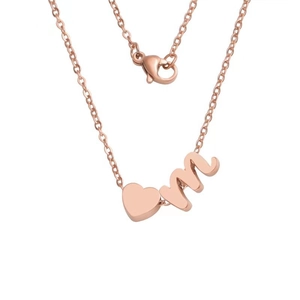 Detail of rose gold heart pendant and lowercase letter m on a delicate chain necklace
