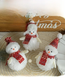 Three plush snowman ornaments with red scarves on a straw mat for Christmas decor