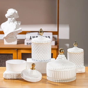 Detail view of large glass jars with golden lids featuring diamond and vertical textures