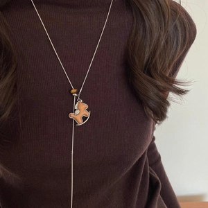 Detail of wooden rocking horse pendant and tiger eye bead on long silver chain