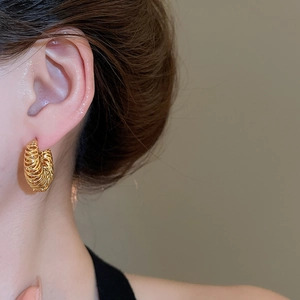 Détail d'une boucle d'oreille créole plaquée or 18k avec un design torsadé texturé