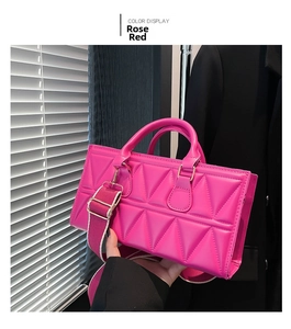 Detail of rose red geometric quilted bag with thick shoulder strap and gold buckle