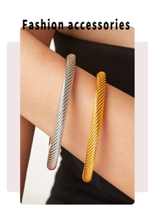 Detail of twisted cable cuff bracelet in gold and silver finish with ball ends