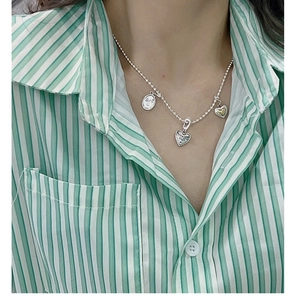 Close-up of S925 sterling silver heart and circle pendants worn on a neck