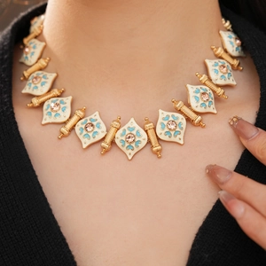 Detail of vintage necklace with enamel rhombus and blue floral pattern on model
