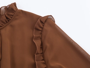 Détail de la robe en mousseline marron foncé avec volants élégants sur le col montant