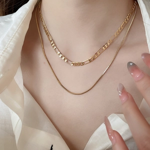 Detailed view of layered 18k gold plated Figaro and snake chains on a female neck