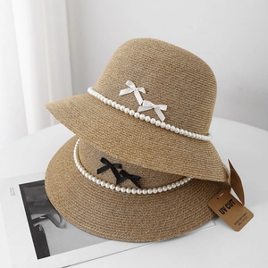 French straw sun hat with pearl chain decoration and elegant bows for beach vacation