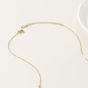 Detail of golden beaded necklace featuring secure lobster clasp and adjustable extension chain