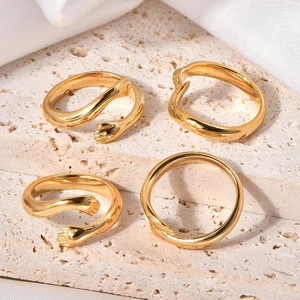 Detail view of four gold-plated hug rings on beige stone and white silk fabric