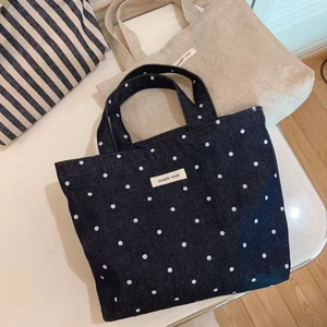 Detail of navy blue polka dot canvas handbag with simple wish embroidered label